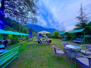 Himalayan Nature Walk Resort, Manali في مانالي: مجموعة من الكراسي والطاولات والمظلات