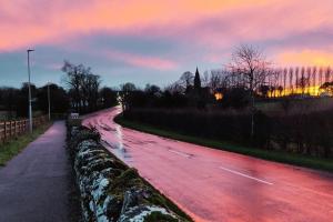 a wet road with a sunset in the background at Secluded Modern Guest House in Castletown Gheoghegan