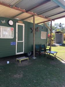 a green trailer with a table and chairs under awning at BERTHA caravan River Heads in River Heads