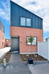 a red brick house with a black garage at Āta Haere - Christchurch Holiday Homes in Christchurch