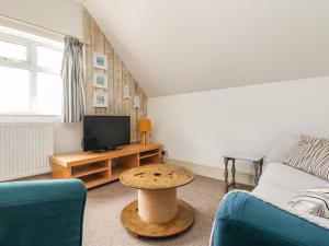 a living room with a couch and a tv and a table at Little Trelawns in Mawgan Porth