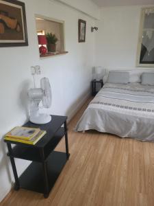 a bedroom with a bed and a table with a fan at le bungalow au fond du jardin in Valeille