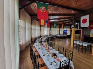 una lunga sala da pranzo con tavoli, sedie e bandiera di Mountain Base ARTUCH a Panjakent