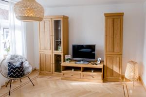 a living room with a television on a wooden cabinet at Ferienwohnung Wildfang in Blankenburg