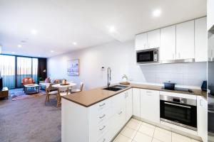 uma cozinha com armários brancos e uma sala de estar em Arte Apartments Braddon em Camberra