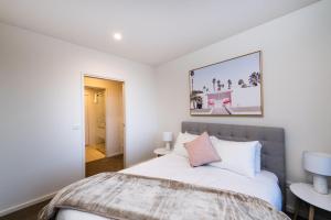 um quarto branco com uma cama e uma mesa em Arte Apartments Braddon em Camberra