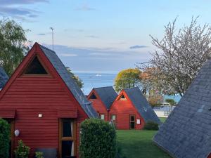 een rij rode huizen met de oceaan op de achtergrond bij Pebbles Seaside Lodge in Kent