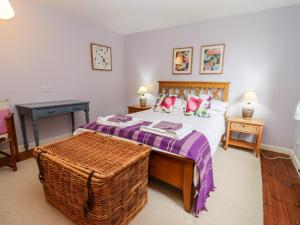 a bedroom with a bed and a wicker table at Yew Tree Cottage in Great Malvern