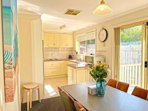 a kitchen with a table with a vase of flowers on it at Charming Convenient 2BR Compact House Ringwood in Ringwood