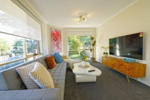 a living room with a couch and a large tv at Charming Convenient 2BR Compact House Ringwood in Ringwood