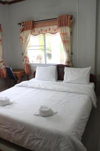 Una cama blanca con dos toallas blancas encima. en Theokhame Guest House & Hotel, en Ban Tayun