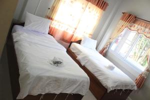 2 camas individuales en una habitación con ventana en Theokhame Guest House & Hotel, en Ban Tayun
