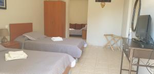 een hotelkamer met 2 bedden en een televisie bij Notia Gi in Kali Limenes