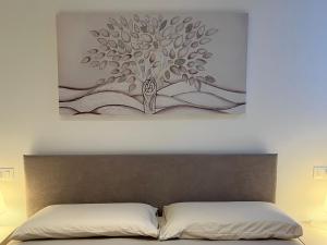 a painting of a tree on the wall above a bed at LUCE in Bologna