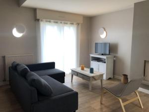 ein Wohnzimmer mit einem Sofa und einem TV in der Unterkunft Maison avec jardin au calme proche centre-ville in Vannes