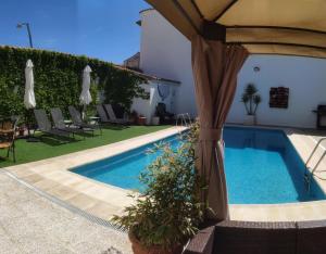 een zwembad met een parasol en stoelen en een zwembad bij Casa Capricho del Destino 