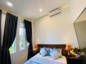 a bedroom with a bed with pillows and a window at Mia's House Hue in Thôn Kim Long (1)