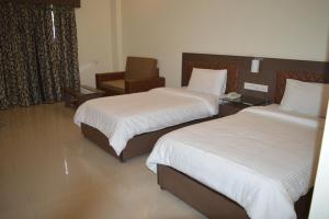 a hotel room with two beds and a chair at Hotel Sravasti Residency in Katra