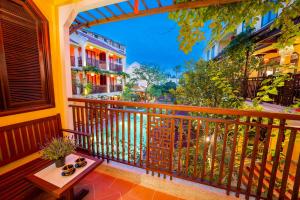 a balcony with a wooden railing and a table at Ahoy Hoi An Boutique Resort & Spa in Hoi An