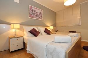 sypialnia z dużym białym łóżkiem z 2 lampami w obiekcie Luxury Maraschino Apartments w mieście Zadar