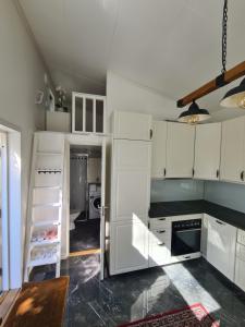 a kitchen with white cabinets and a black counter top at TG Oasis Örgryte Stugor & Rum in Gothenburg