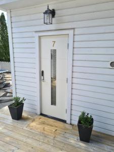 Una porta bianca su una casa con due piante in vaso di TG Oasis Örgryte Stugor & Rum a Göteborg