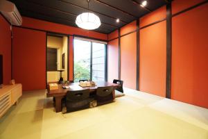 ein Esszimmer mit orangefarbenen Wänden sowie einem Tisch und Stühlen in der Unterkunft MUSUBI Sanjo Bettei in Shimo-dachiyuuridōri