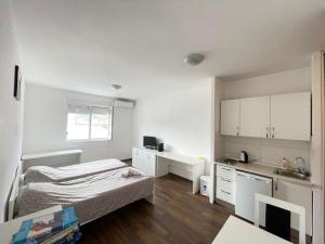 a small white room with a bed and a kitchen at City Apartments in Mostar