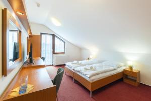 a bedroom with a bed and a desk and a tv at Penzion Jas in Luhačovice