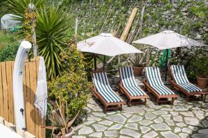 - un ensemble de chaises et de parasols sur une terrasse dans l'établissement Casa Romelide Positano Amazing view on Amalfi Coast, à Positano
