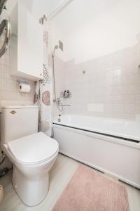 een badkamer met een toilet, een bad en een wastafel bij Bright Apartment near the Mall in Kaunas
