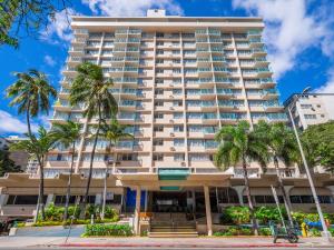 a tall building with palm trees in front of it at Penthouse in Waikiki with ocean & mountain views in Honolulu