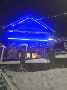 um edifício coberto de neve à noite com luzes azuis em Casa Bran em Buşteni