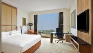 a hotel room with a bed and a desk and a television at Bengaluru Marriott Hotel Whitefield in Bengaluru