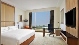 Habitación de hotel con cama, escritorio y TV. en Bengaluru Marriott Hotel Whitefield, en Bangalore