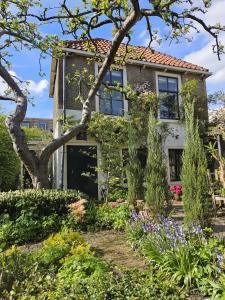 uma casa com um jardim em frente em Apple Tree Cottage - discover this charming home at beautiful canal in our idyllic garden em Gouda