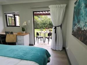 a bedroom with a bed and a table and a window at The Bird Hide Luxury Self catering in White River