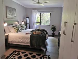 een slaapkamer met een bed met een tafel en een raam bij The Bird Hide Luxury Self catering in White River