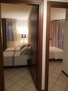 ソンマカンパーニャにあるCozy Homeのベッド2台と鏡付きのベッドルーム1室