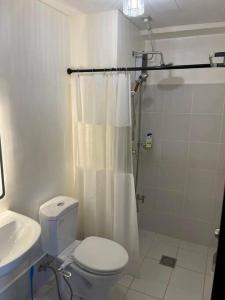 a white bathroom with a toilet and a sink at The Journeyman Suite at Covent Garden Sta Mesa Manila in Manila