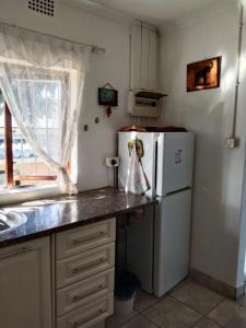une cuisine avec un réfrigérateur blanc et une fenêtre dans l'établissement Jacobs Cottage by the Ocean, à Port Shepstone