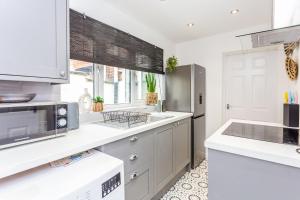 uma cozinha com balcões brancos e um frigorífico de aço inoxidável em Boho Chic - Stylish Home in City Centre, Sleeps 4 em Darlington
