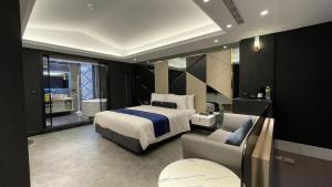 een slaapkamer met een bed, een bank en een stoel bij H Motel璽悅國際精品旅館 in Zhubei