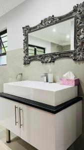 y baño con lavabo blanco y espejo. en Robyns Nest 3 Self Catering Flat, en Kloof