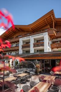 an outdoor patio with tables and chairs and a building at Hotel Lohningerhof in Maria Alm am Steinernen Meer