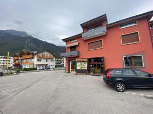 ein schwarzes Auto, das vor einem roten Gebäude parkt in der Unterkunft Maison Faganello Loft in Ponte nellʼAlpi