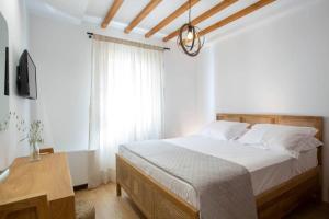 a bedroom with a bed with white sheets and a window at Angestrale Traditional Residence in Lefkada Town