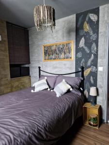 1 dormitorio con 1 cama grande de color púrpura con lámpara de araña en La Parenthèse en Sambin
