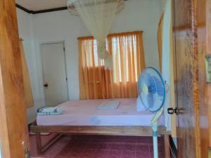 a bedroom with a bed with a fan on it at Fely's Homestay in Batuan