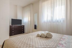 una camera da letto con due asciugamani su un letto con televisore di Appartamento Leo a Brindisi